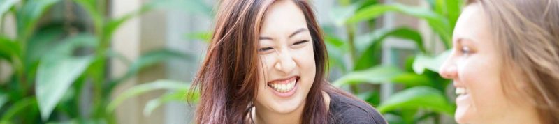 Image depicts two students sitting together and laughing