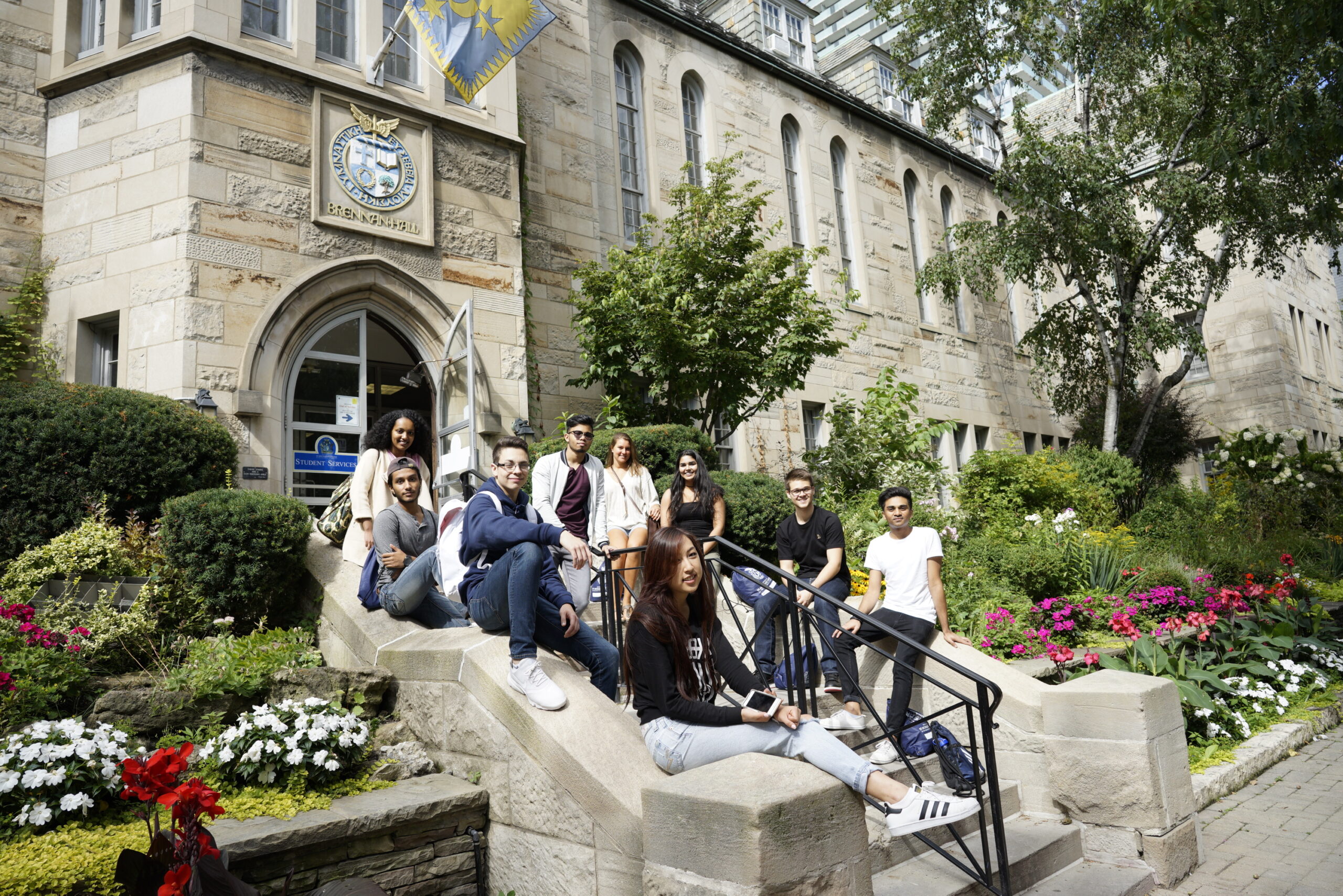 Image depicts a group of students sitting on the steps of Brennan Hall