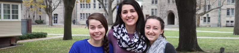 Image depicts three female students in the USMC quad