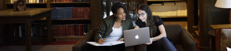 Image depicts two females studying in together in the library