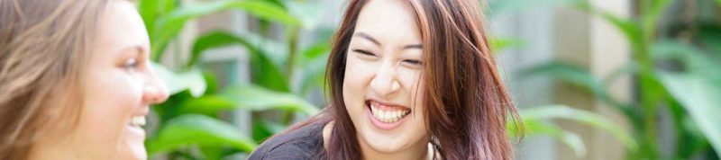 Image depicts two students sitting together laughing