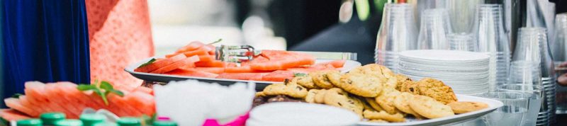Image depicts a try of cookies and fruit on a nicely dressed table