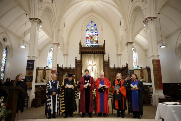 A group stands on stage in St. Basil's in academic robes as the installation ceremony begins. 