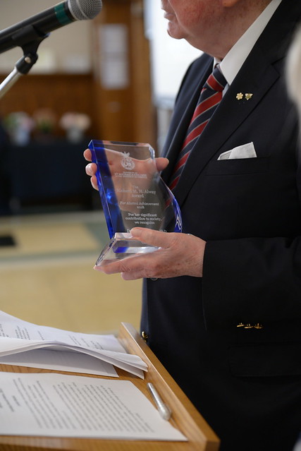 A man holds the Alway Award while speaking at a podium. 