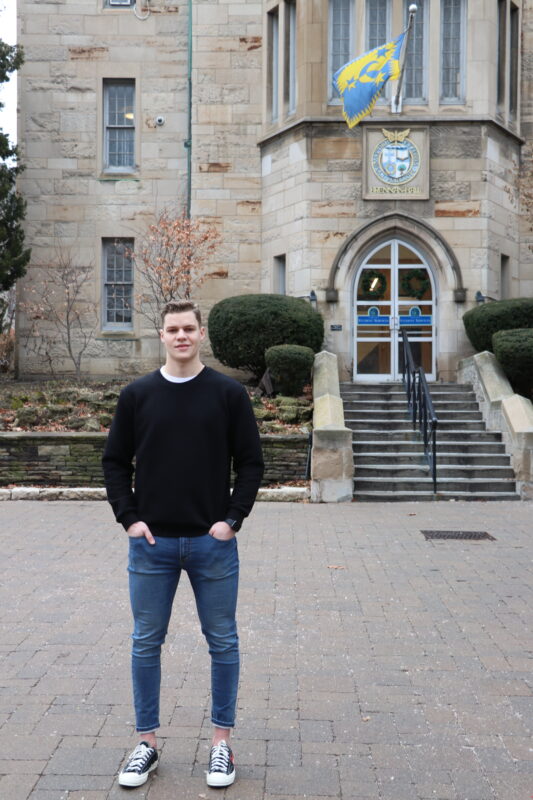 St. Mike's student athlete Kyle Potts stands in front of Brennan Hall on campus. 