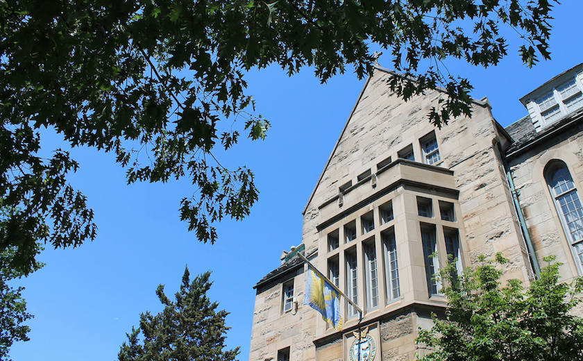 Image depicts the southern facade of Brennan Hall on a sunny summer day.