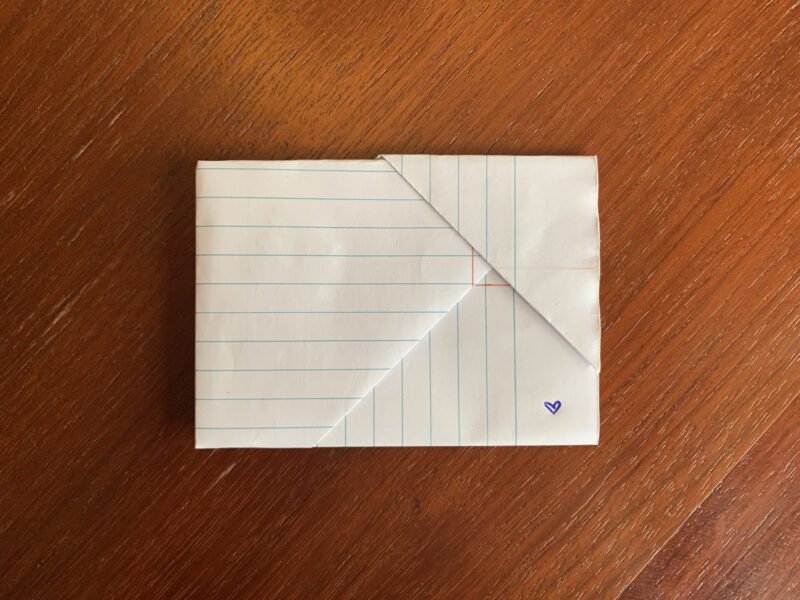 Image depicts a folded piece of notebook paper sitting on a table. 