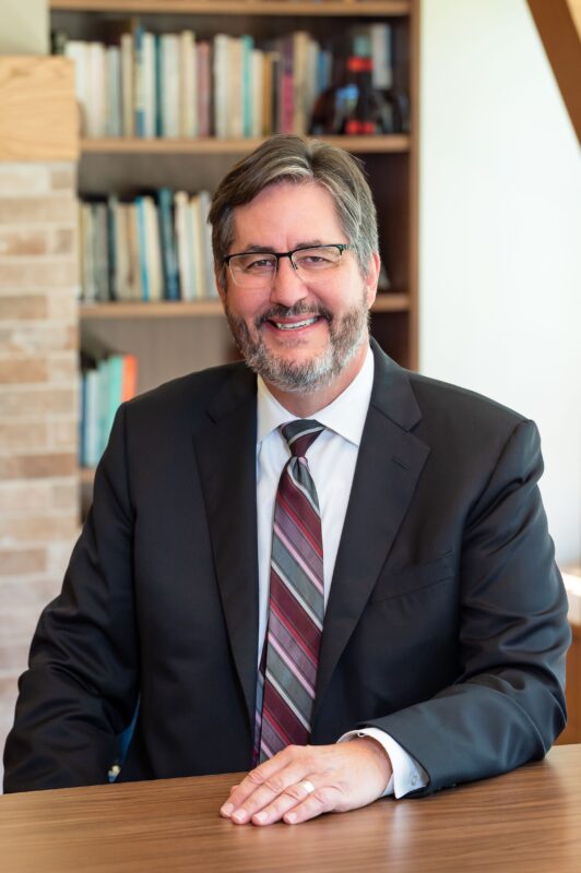 Image depicts St. Michael's president David Sylvester seated at a table in his office on campus.