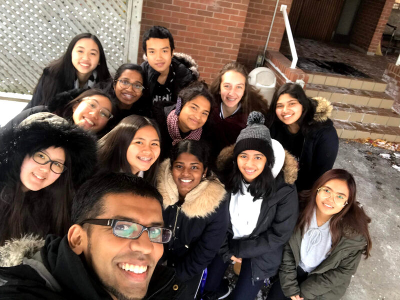 Image depicts MRE student Andrew Selvam taking a selfie with a group of students. 