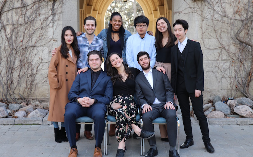 Image depicts a group of residence dons posing together in front of an outdoor archway on the St. Michael's campus