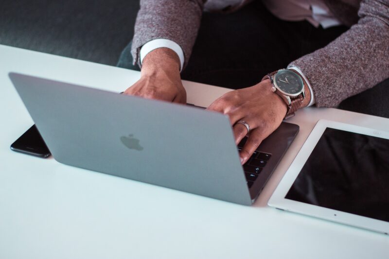 Image depicts a man's hands as he works on a laptop 