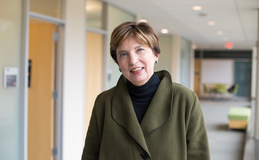 Image depicts Dr. Hilda Koster standing in front of a long hallway