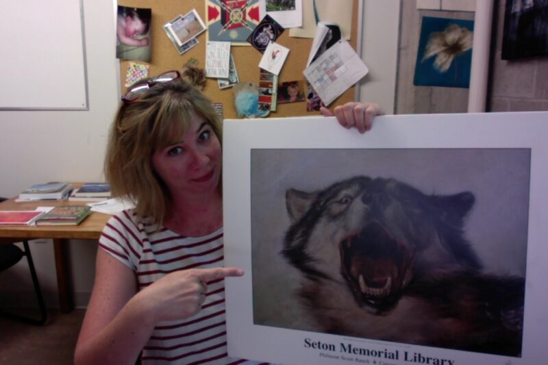 Photograph of Dr Rutherford pointing at a photo of a wolf