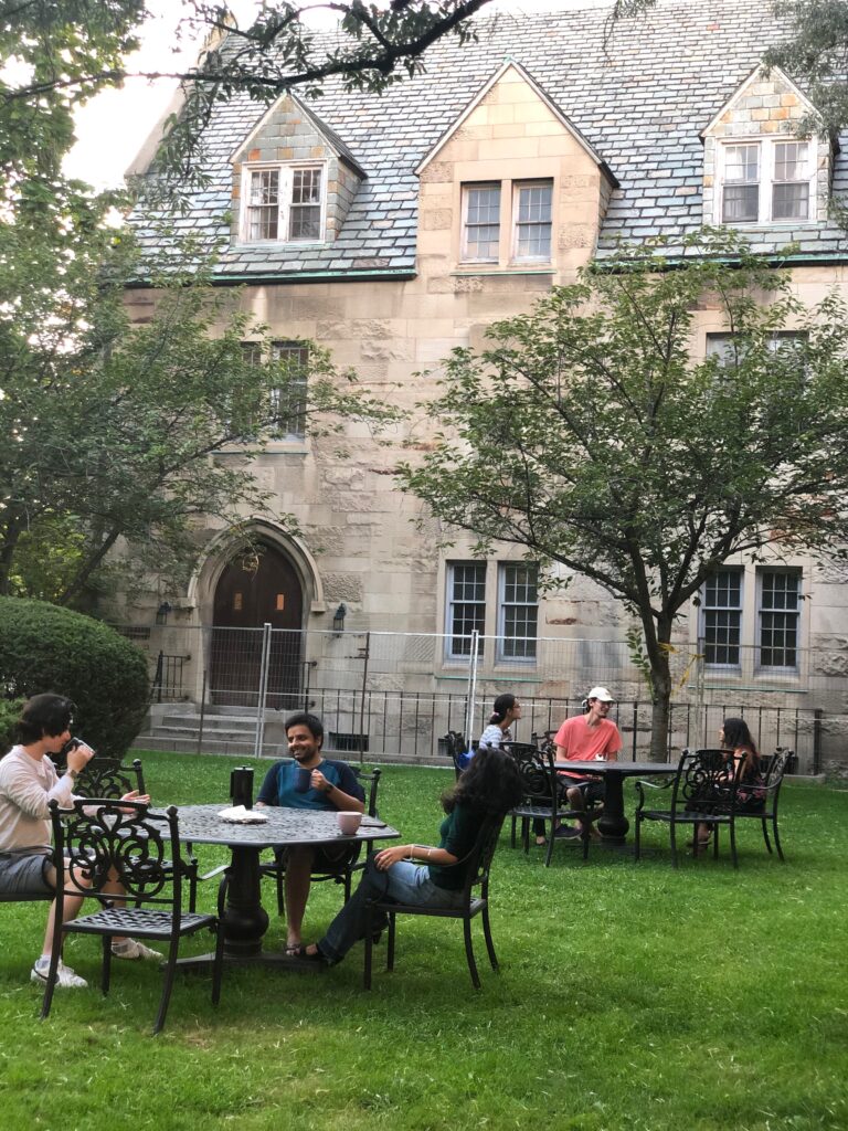 Students sit together at outdoor tables in a small parkette at St. Michael's 