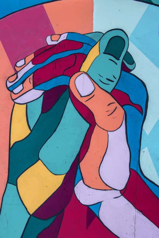Mural of two bright, multicoloured hands interlocking