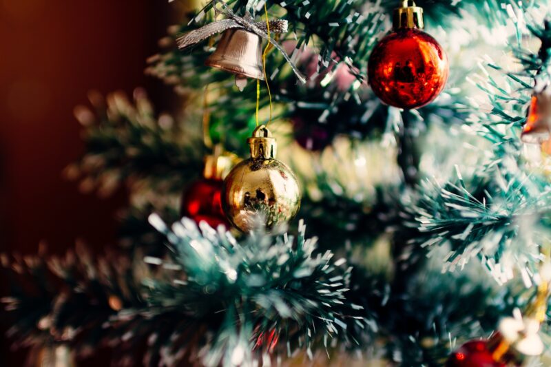 Christmas ornaments hang off the branches of a decorated tree