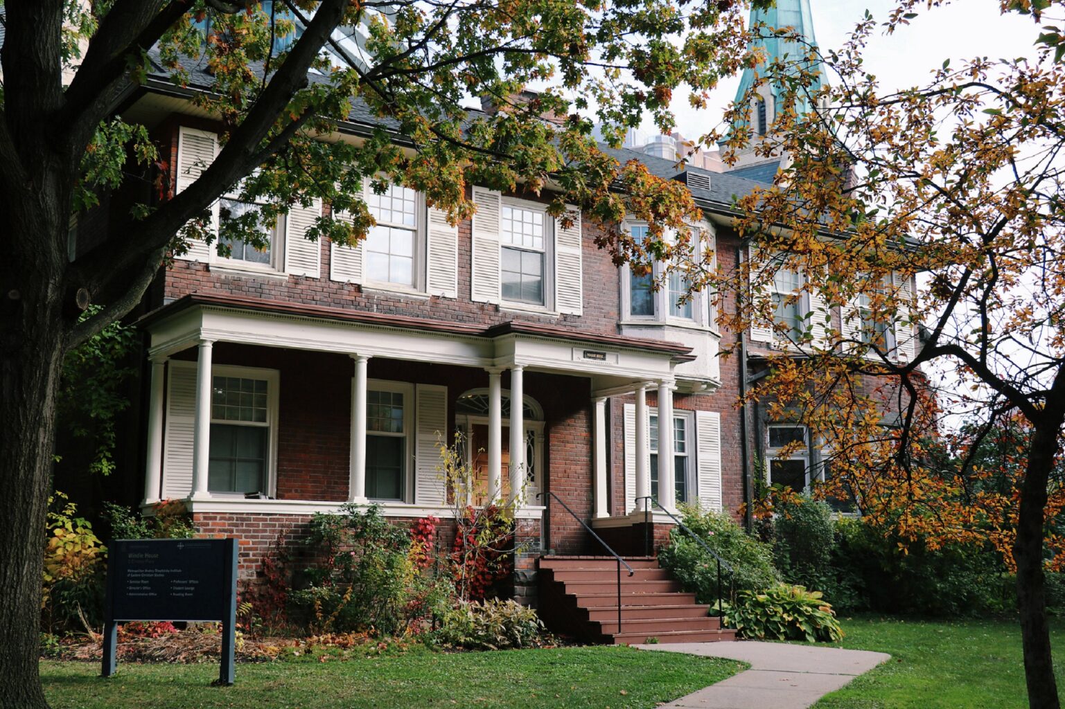 Photograph of Windle House on the St. Mike's campus with the steeple of St. Basil's in the background