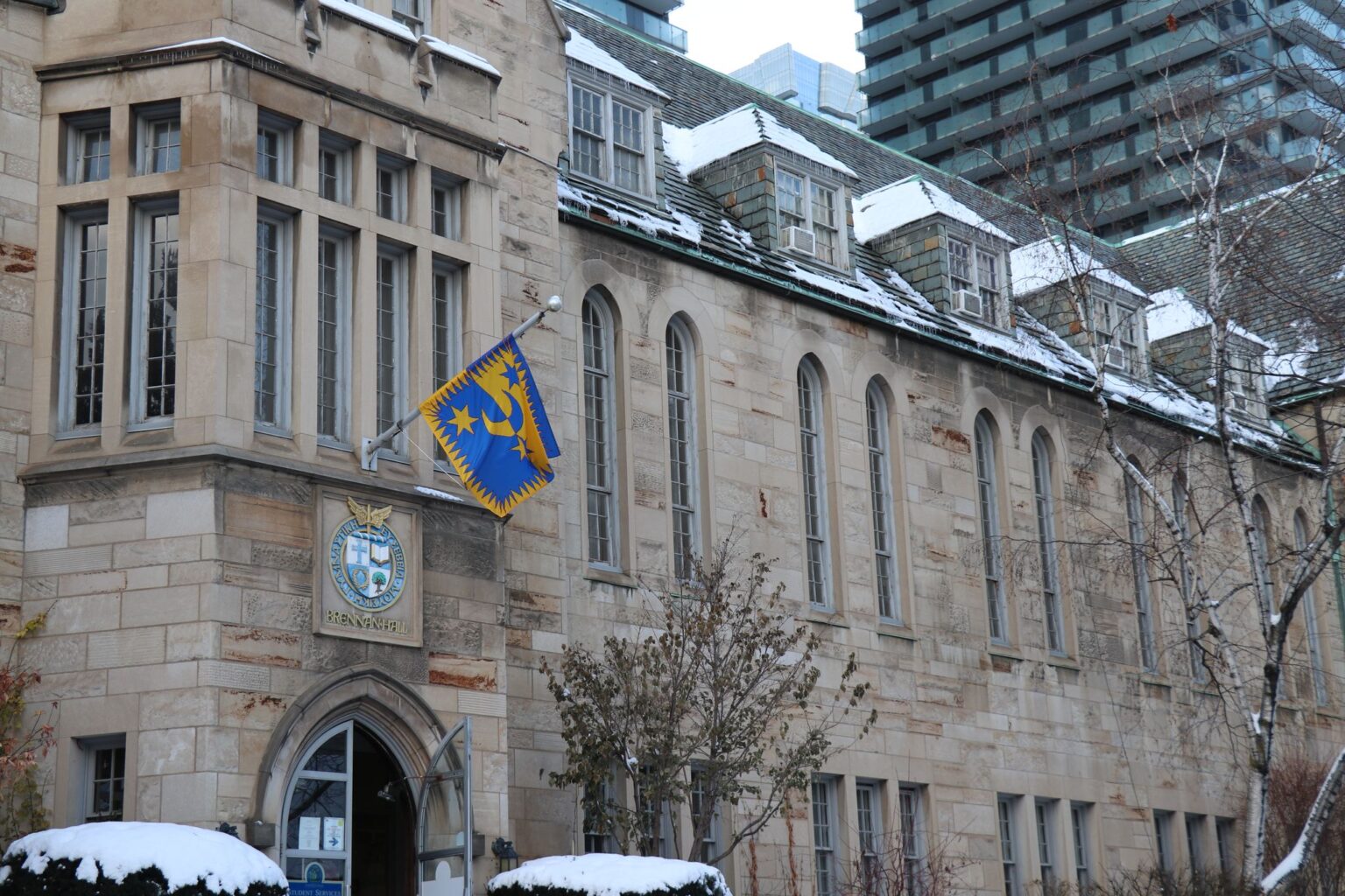 Brennan Hall in wintertime with snow visible on the roof and shrubbery