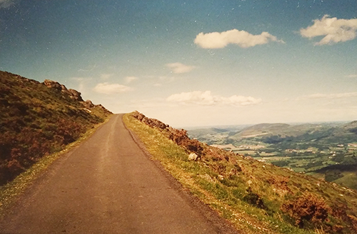 Outdoors, a mountain path next to a drop-off into a valley 