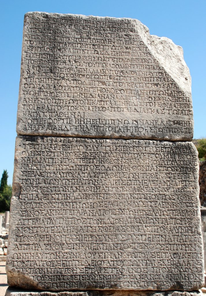 Photograph of two large stone blocks carved with Ancient Greek writing against a blue sky background.