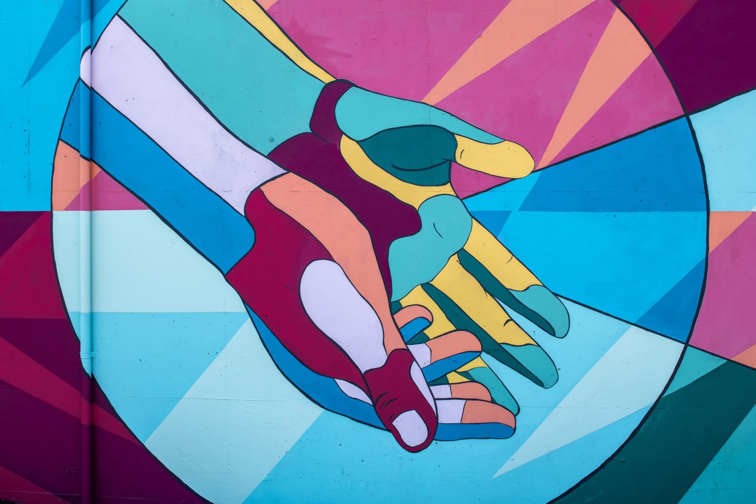 Wall mural of two brightly coloured hands, palms facing upward, with a circle surrounding them