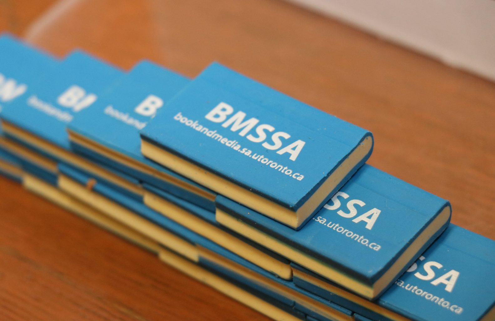 Close up photograph of a pyramid of Book and Media Studies branded erasers shaped like books.