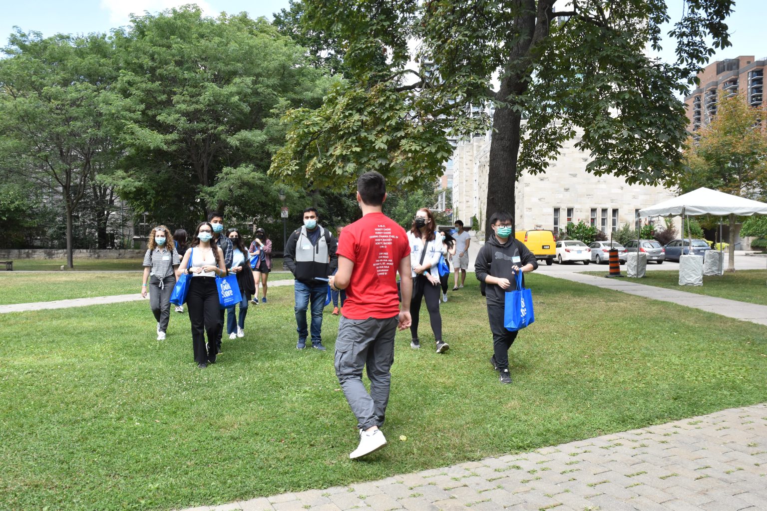 Photograph of new St. Mike's students walking on the St. Mike's quad, following an orientation leader with his back to the camera