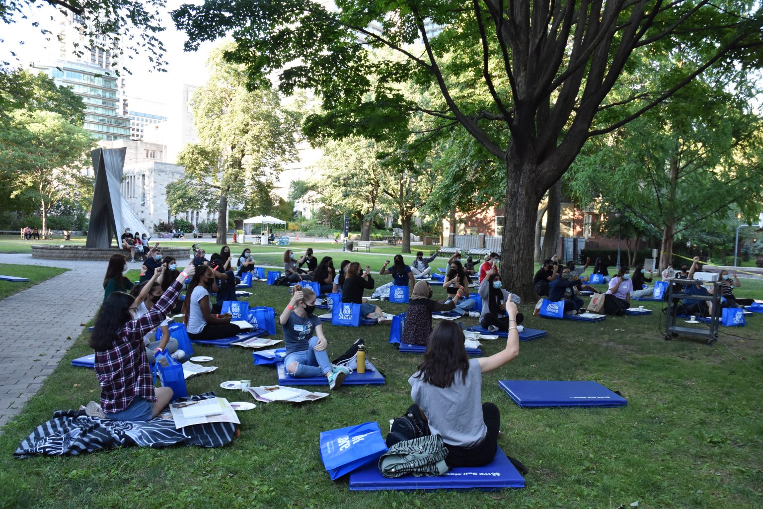 Photograph of physically distanced students on the St. Mike's quad raising their hands during a presentation.
