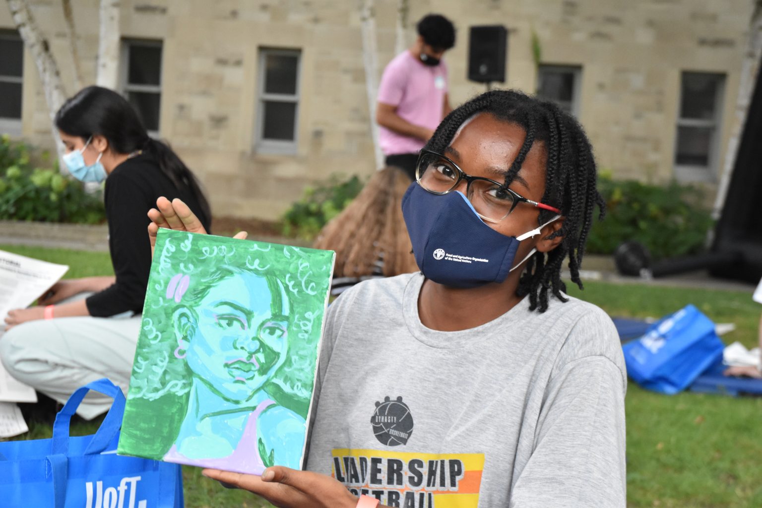 Photograph of a new St. Mike's student holding a graphic portrait painting