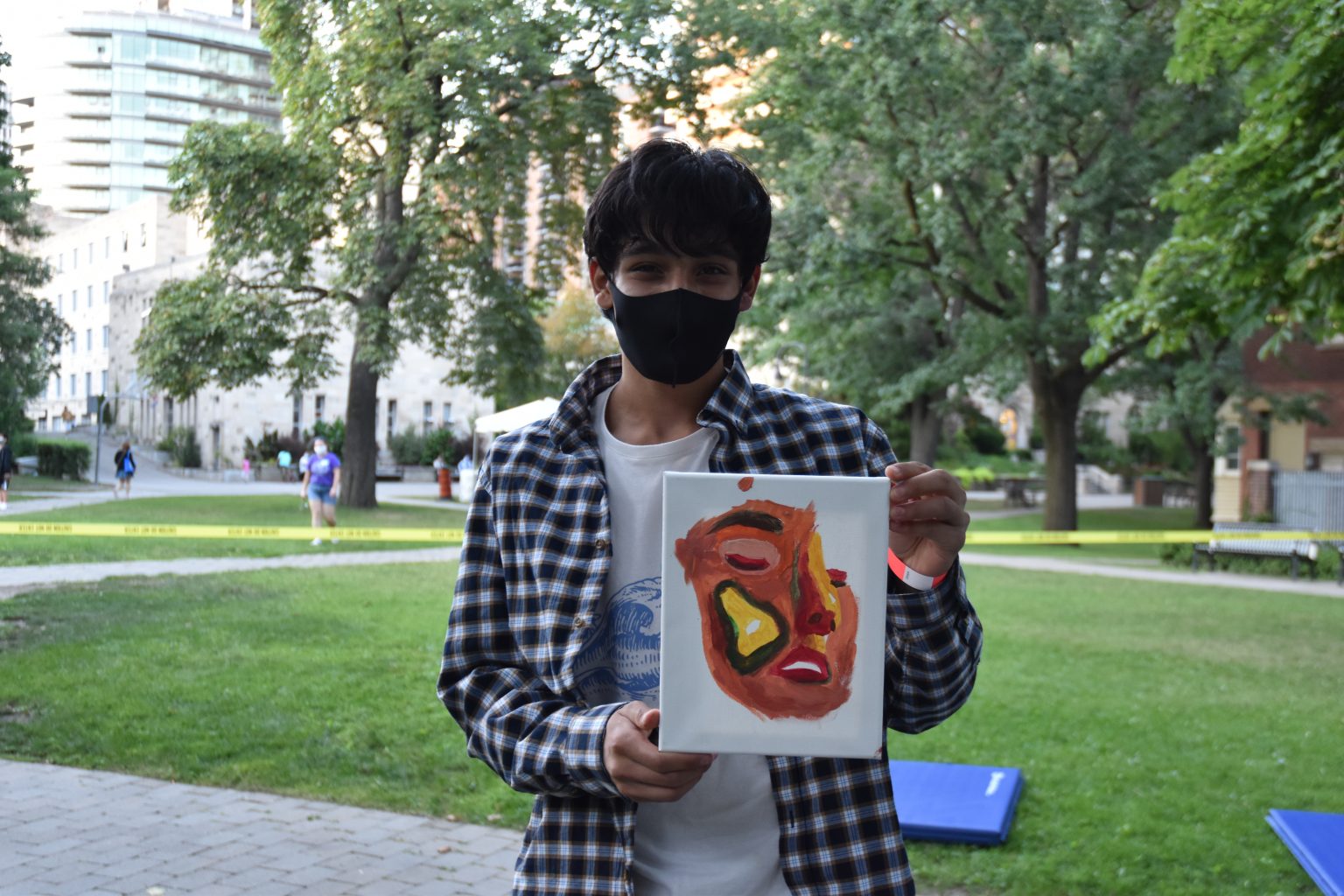 Photograph of a new St. Mike's student holding up a graphic painting of a face