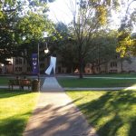 The Quad at St. Michael's with trees, benches, buildings, and an abstract metal sculpture visible