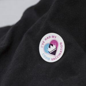 A COVID vaccination sticker on a garment