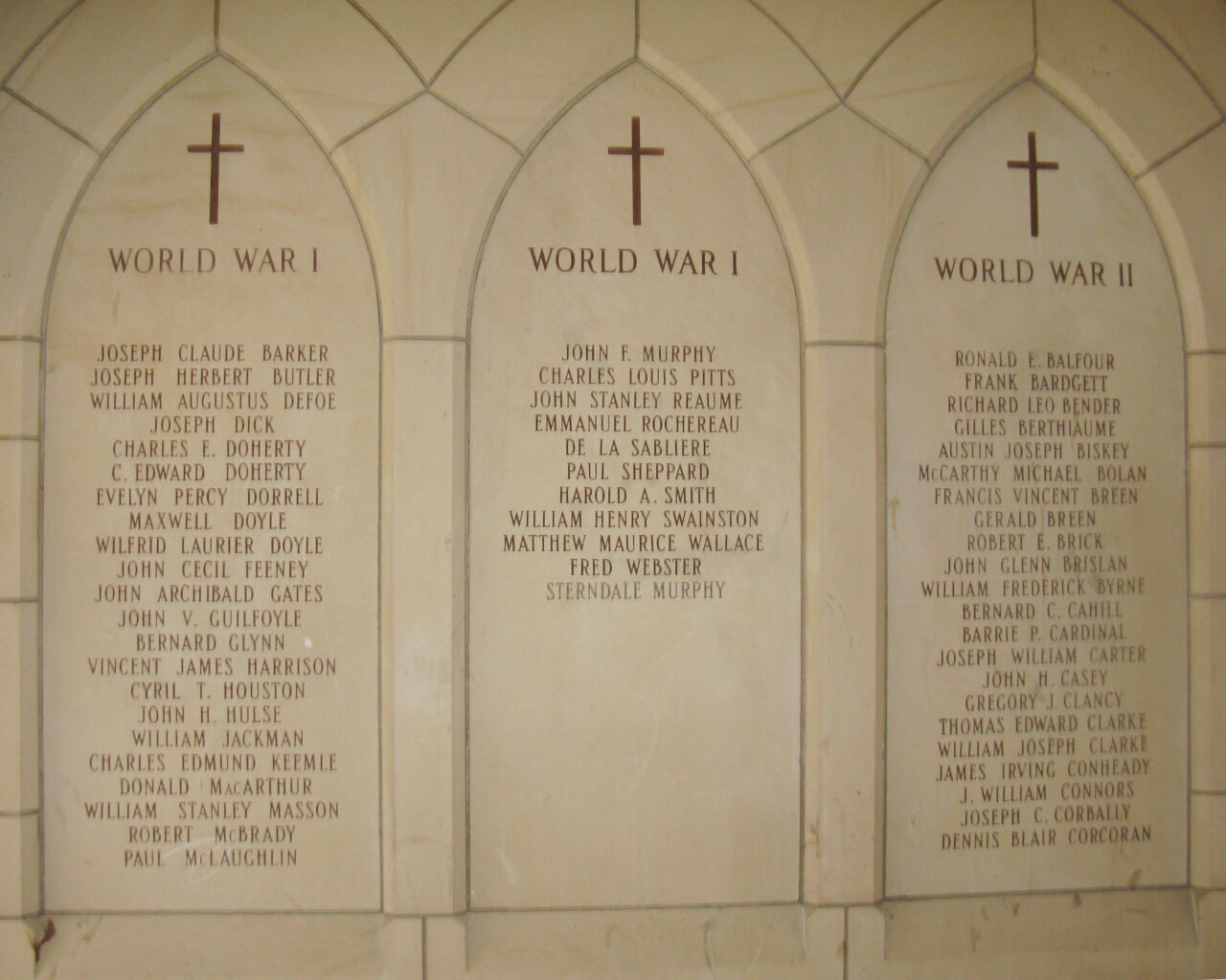 Photograph of the interior of the St. Michael's Soldiers’ Memorial Slype. Three panels include inscriptions of Crosses and "World War I" or "World War II" with lists of names.