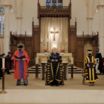 Five people in academic regalia stand together in front of the altar in St. Basil's Church during Fall Convocation 2021