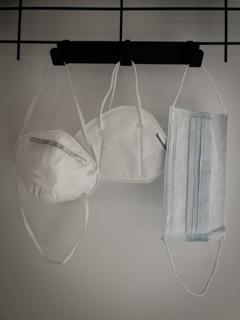 Photograph of three different medical masks hanging from hooks on the wall.