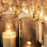 Rows of lit candles in cylindrical holders