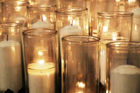 Rows of lit candles in cylindrical holders