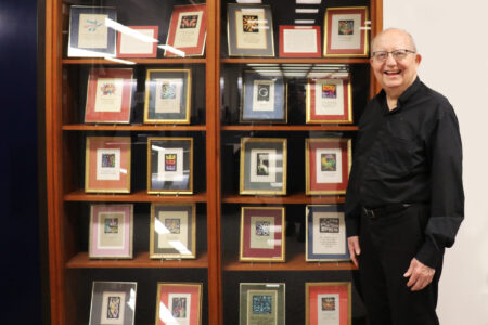 Father Farge stands in front of a display of his handmade Christmas cards.