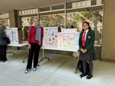 Highschool students stand in front of their projects outside the Kelly Library