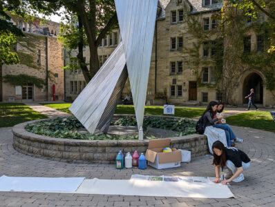 Students paint a banner at the base of St. Michael's statue