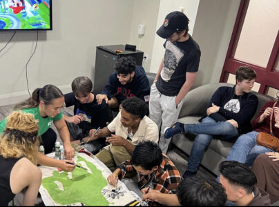 Elijah and peers painting a banner for Dean's Cup