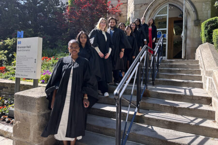 graduands in convocation gowns outside Brennan Hall