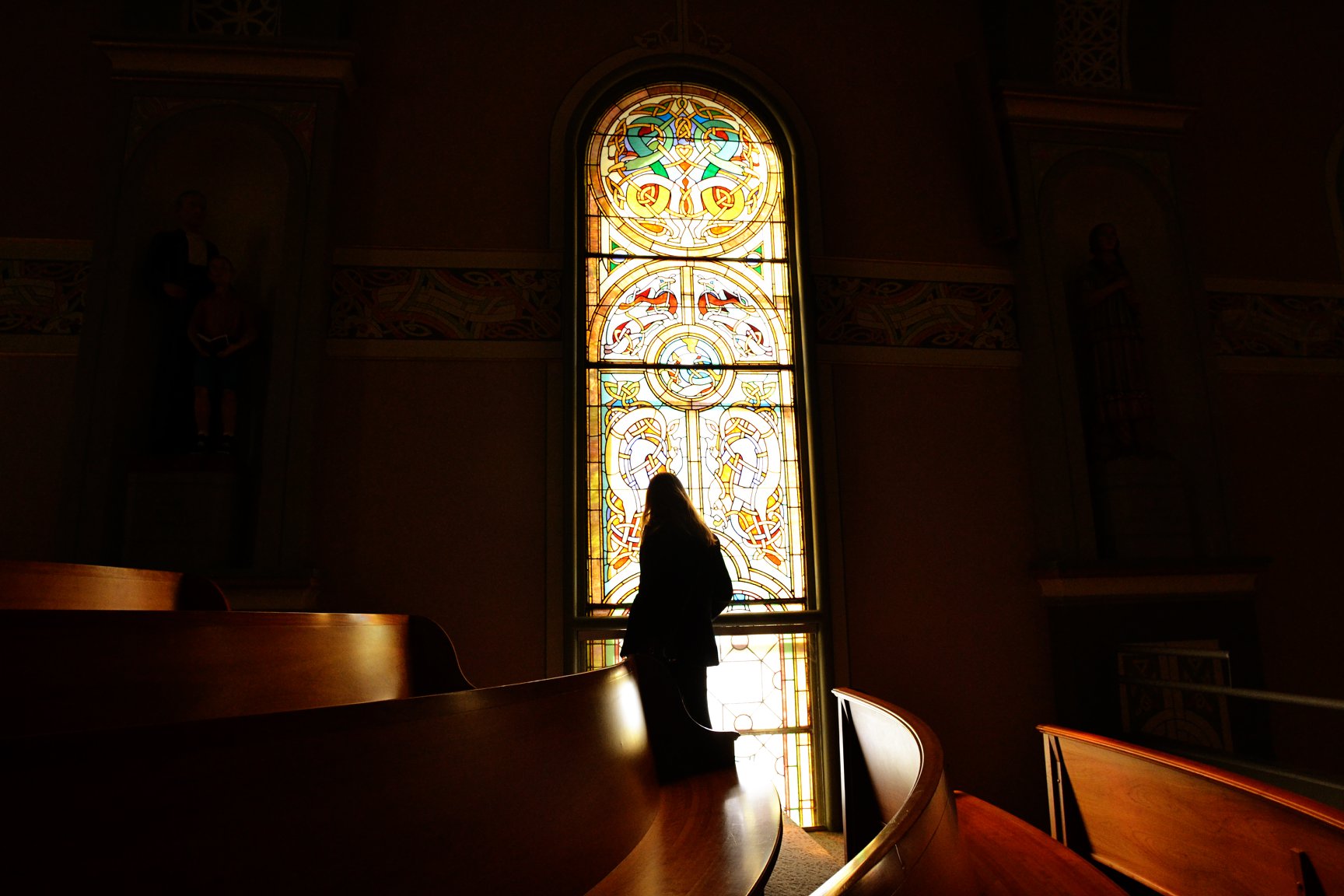 a figure in front of a church stained glass window